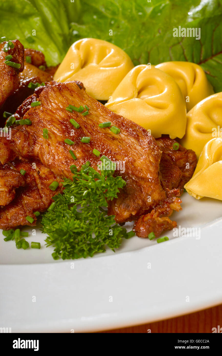 Gebratenes Huhn mit frischen grünen Salat und Tortellini Nudeln auf einem weißen Teller Stockfoto