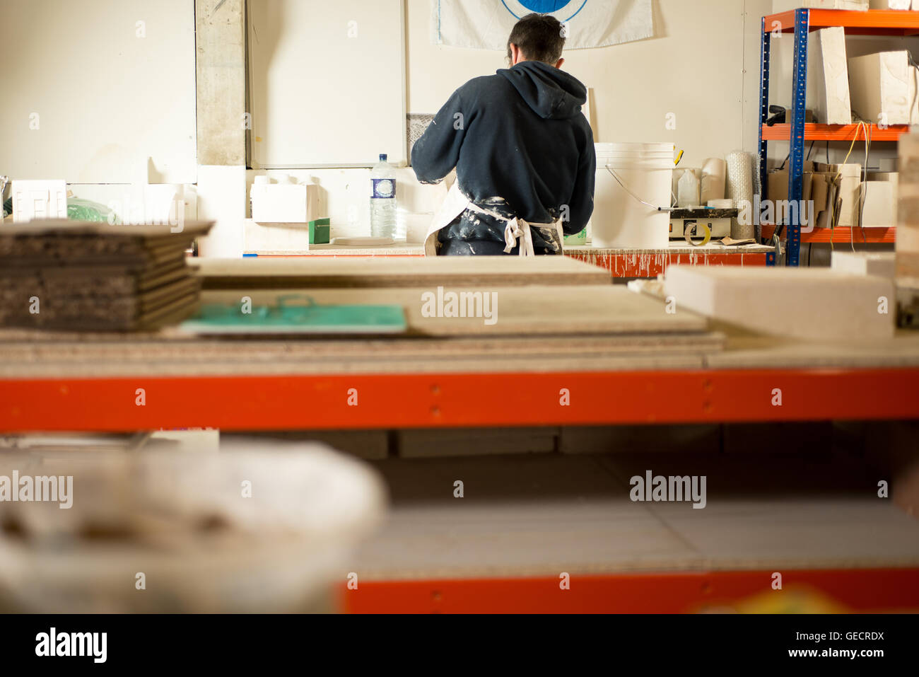 Ein Mann in Gips bespritzt-Kleidung mit Rücken drehte arbeiten durch eine  riesige Zeichentisch mit Gipsformen und Modelle Stockfotografie - Alamy