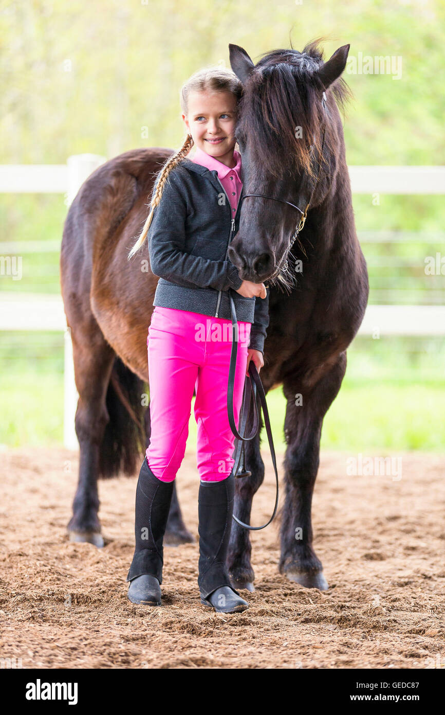 Shetland-Pony. Kind im Kleid stehen neben schwarzen Erwachsenen Reiten. Deutschland Stockfoto