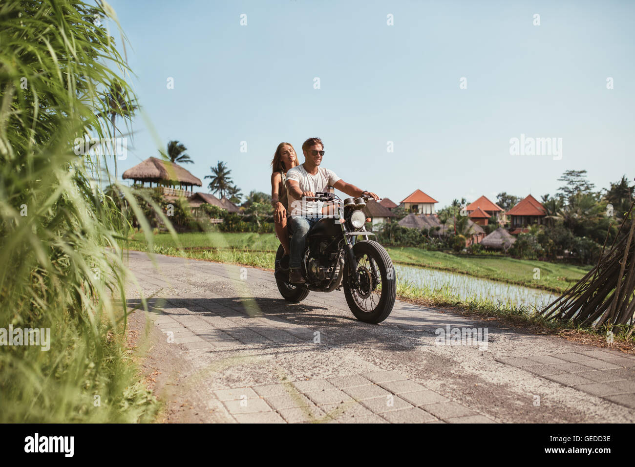 Aufnahme des jungen Paares auf dem Motorrad auf der Landstraße. Junger Mann und Frau außerhalb Motorradfahren an einem Sommertag. Stockfoto