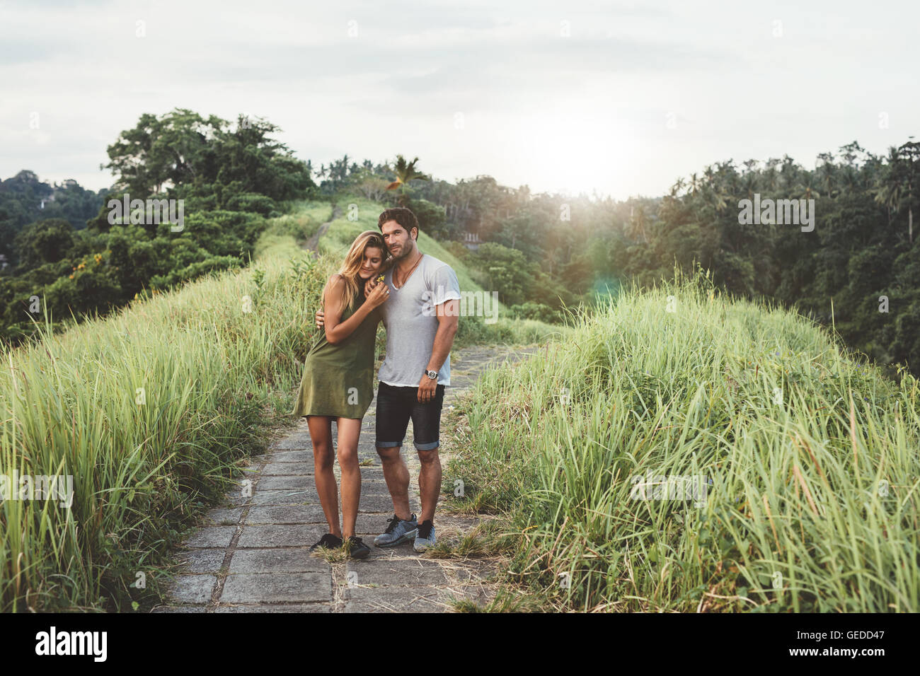 Im Freien Schuss der jungen Paare, die zusammen über Landstraße. Junger Mann und Frau in der Liebe, ein Spaziergang in der Wiese. Stockfoto