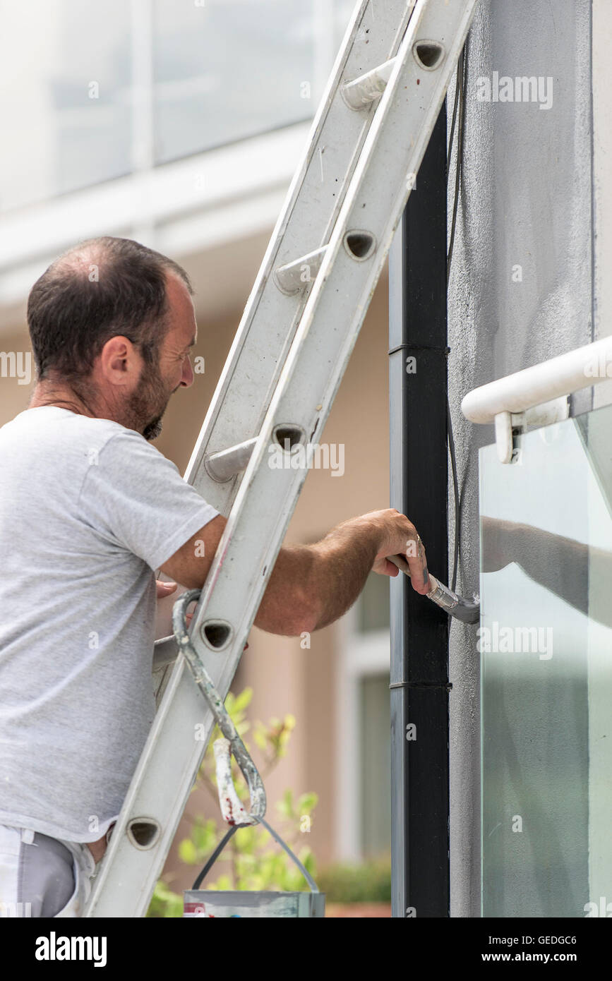 Maler und Dekorateur malt die Außenwand eines Hauses. Stockfoto