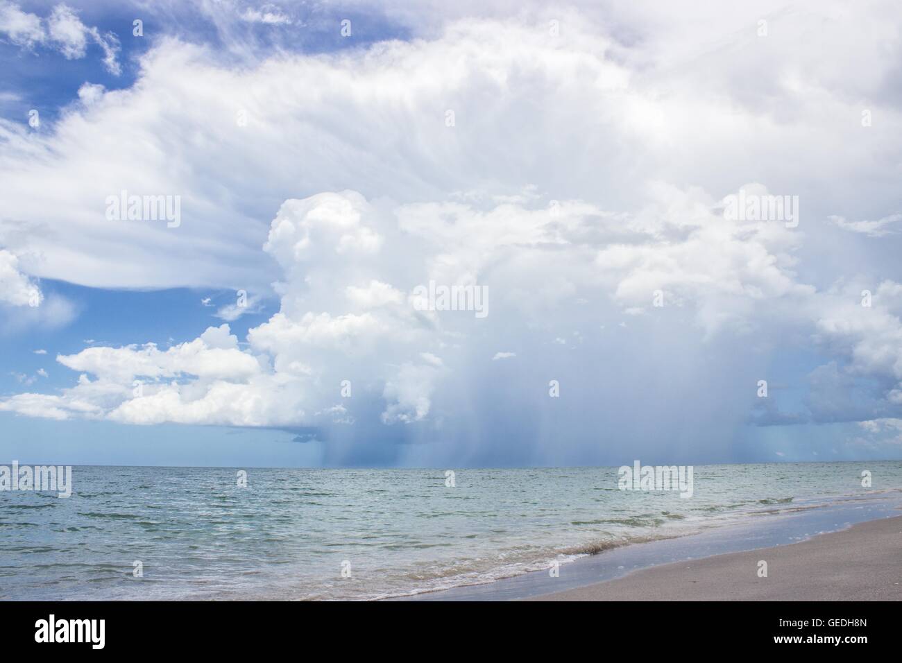 einem fernen Gewitter über dem Wasser an einem Strand, große Wolke und Regen sichtbar Stockfoto