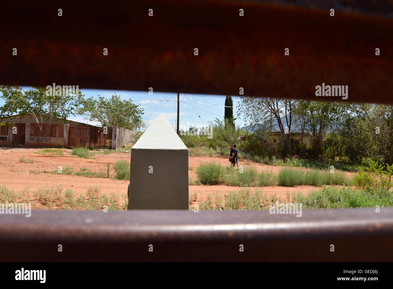 Eine Lücke in der aktuellen Metal Grenzmauer zeigt Jugendliche in Mexiko und die ursprüngliche konkrete Grenzstein in Naco, Arizona, USA. Stockfoto