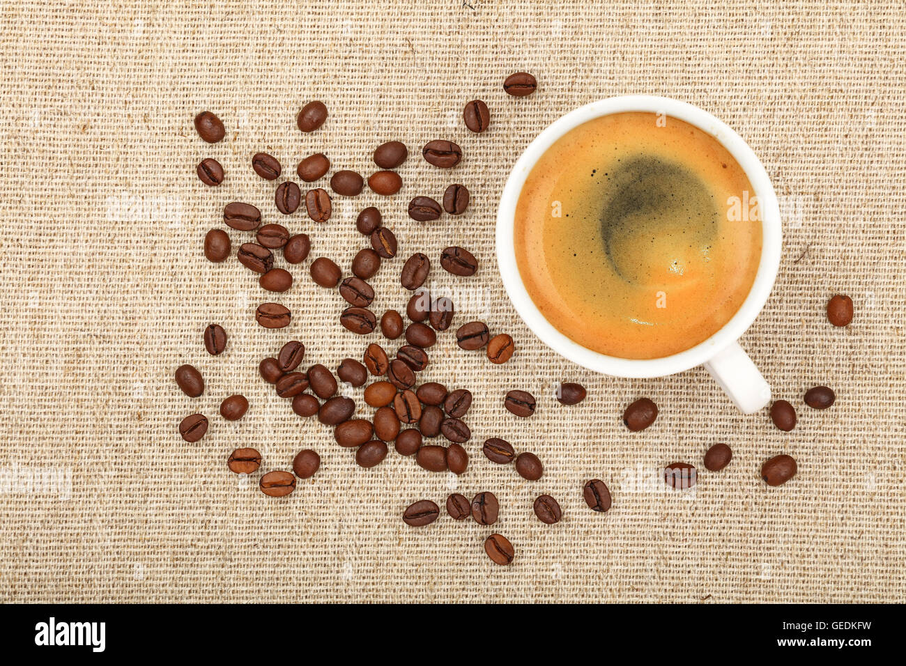Eine weiße Tasse Espresso oder Americano und gerösteten Kaffeebohnen auf Hintergrund der Leinwand Stockfoto