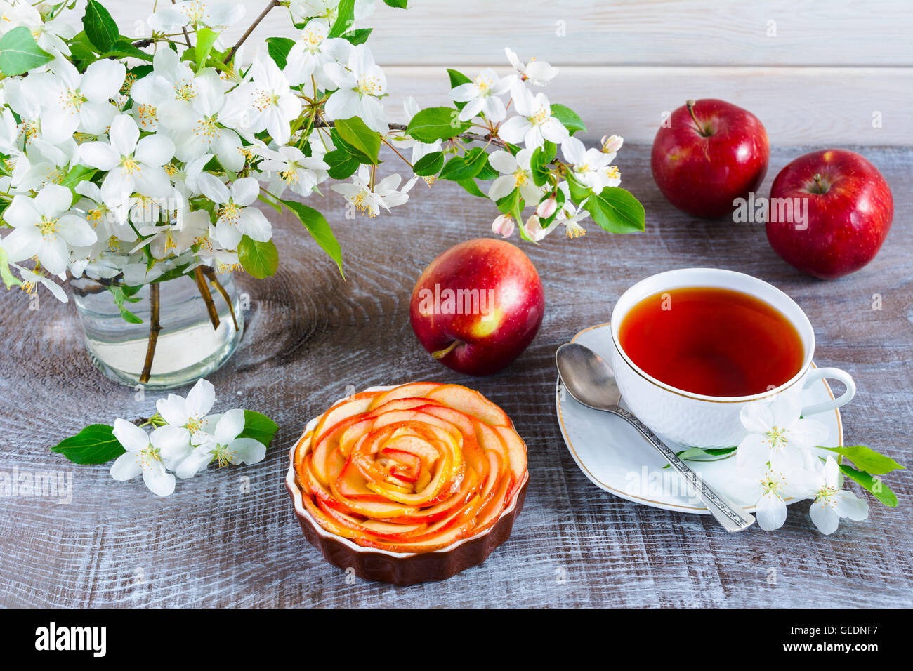 Apple stieg geformte Kuchen und Tee am Holztisch. Apfelkuchen für Tea-Time. Frühstückstee mit süßen Apfel Gebäck. Stockfoto