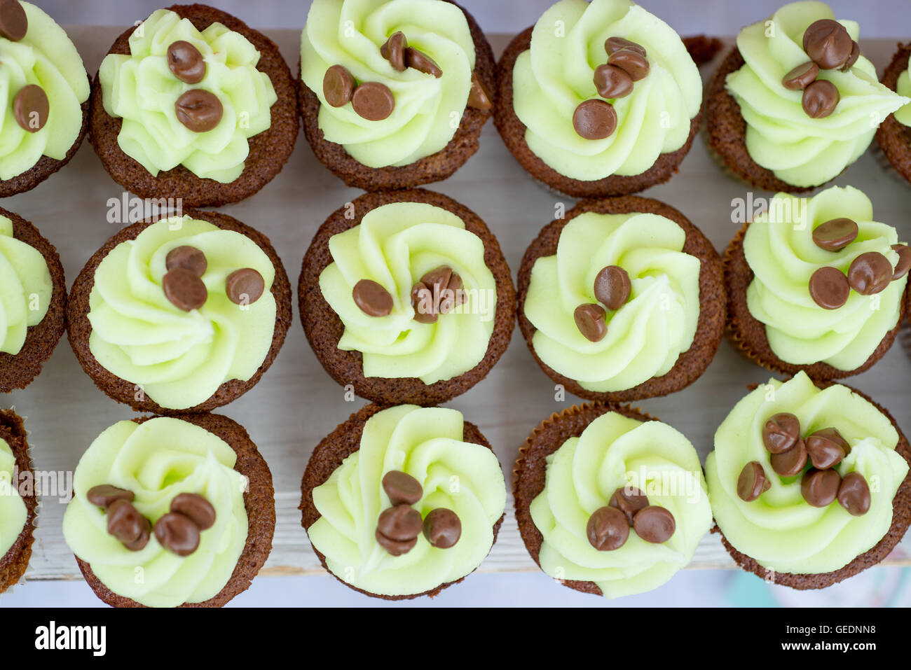 Reihen von Hand dekoriert Cupcakes mit farbigen Glasur grüner Minze und Schokolade-Chips an der Spitze über Kopf gedreht Stockfoto