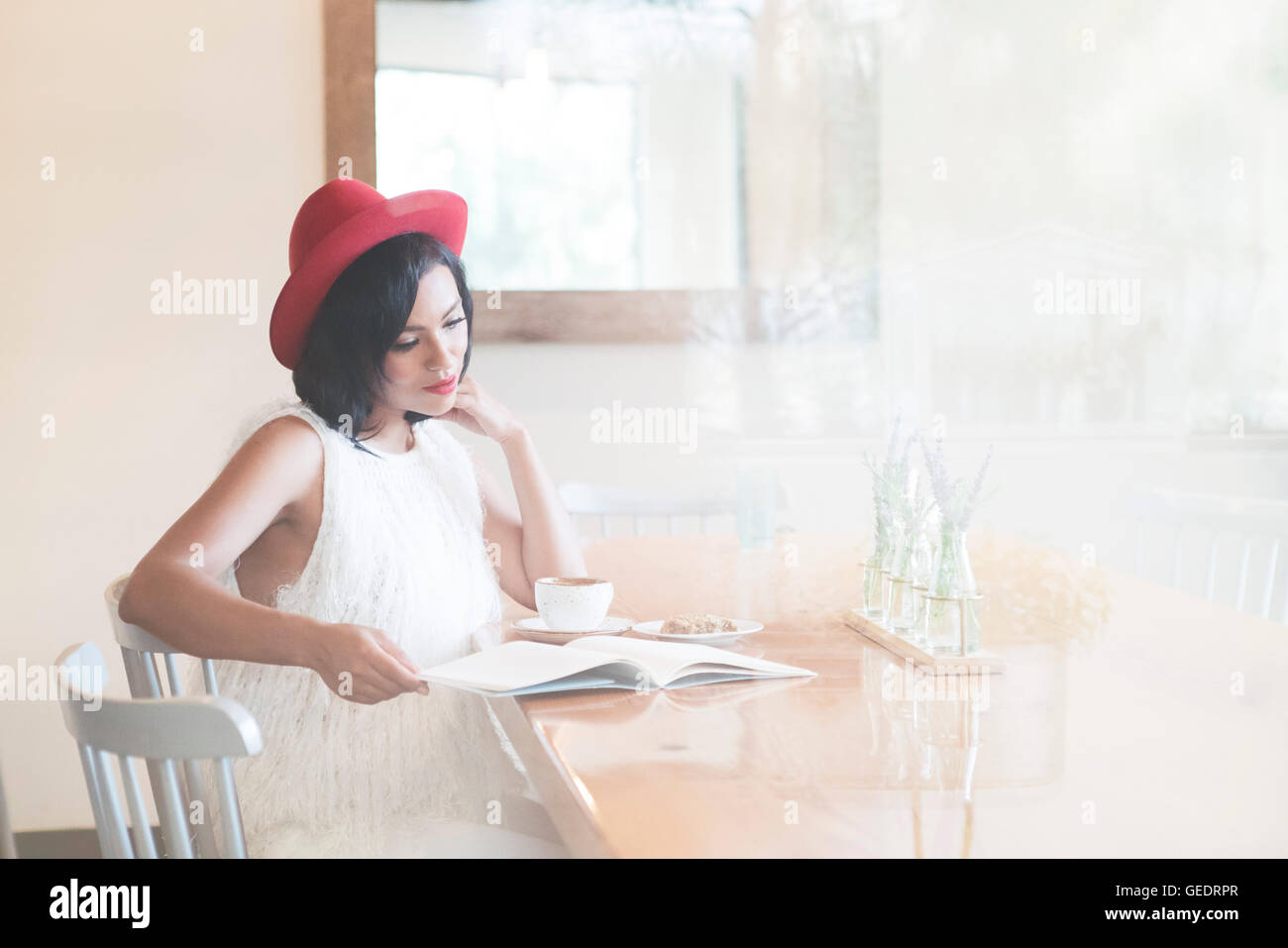 Frau in rot Hut Lesung beim Kaffee trinken Stockfoto