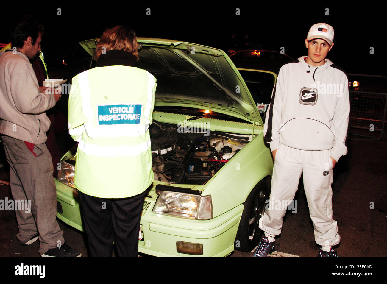 Fahrzeug-Inspektoren überprüfen, dass ein Junge Rennfahrer Auto Straße MOBOGENIE Southend, Basildon 2002 Stockfoto