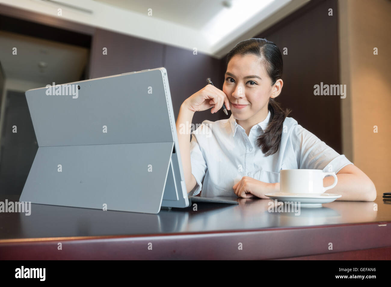 intelligente zuversichtlich Business Frau Porträt. einerseits halten Sie Lächeln Stift. sitzen mit tablet-Laptop-Computer mit Kaffeetasse. Stockfoto