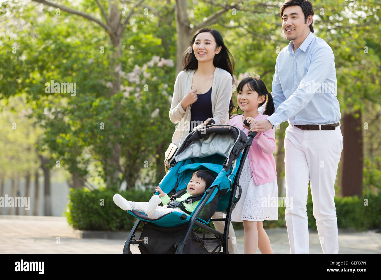 Junge chinesische Familie mit Baby im Kinderwagen spazieren Stockfoto