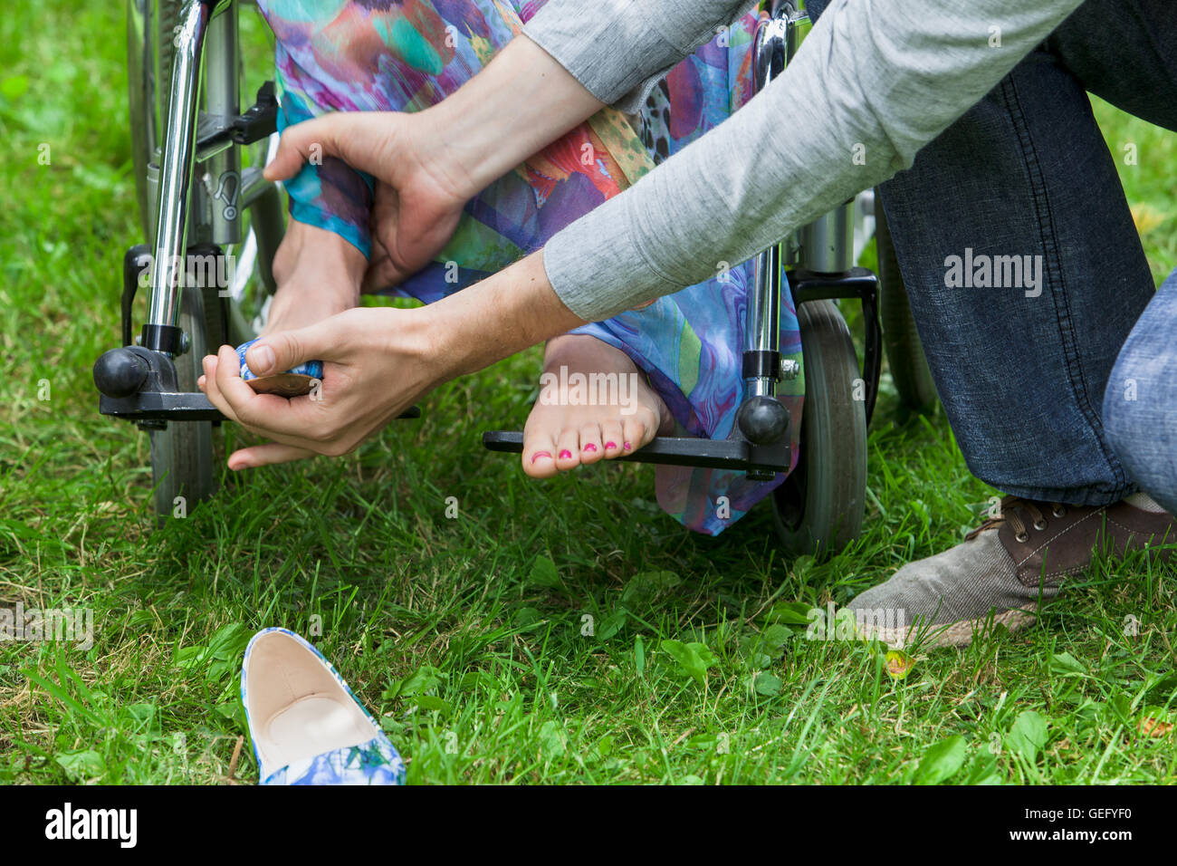 Mann hilft behinderte Frau im Rollstuhl Stockfoto