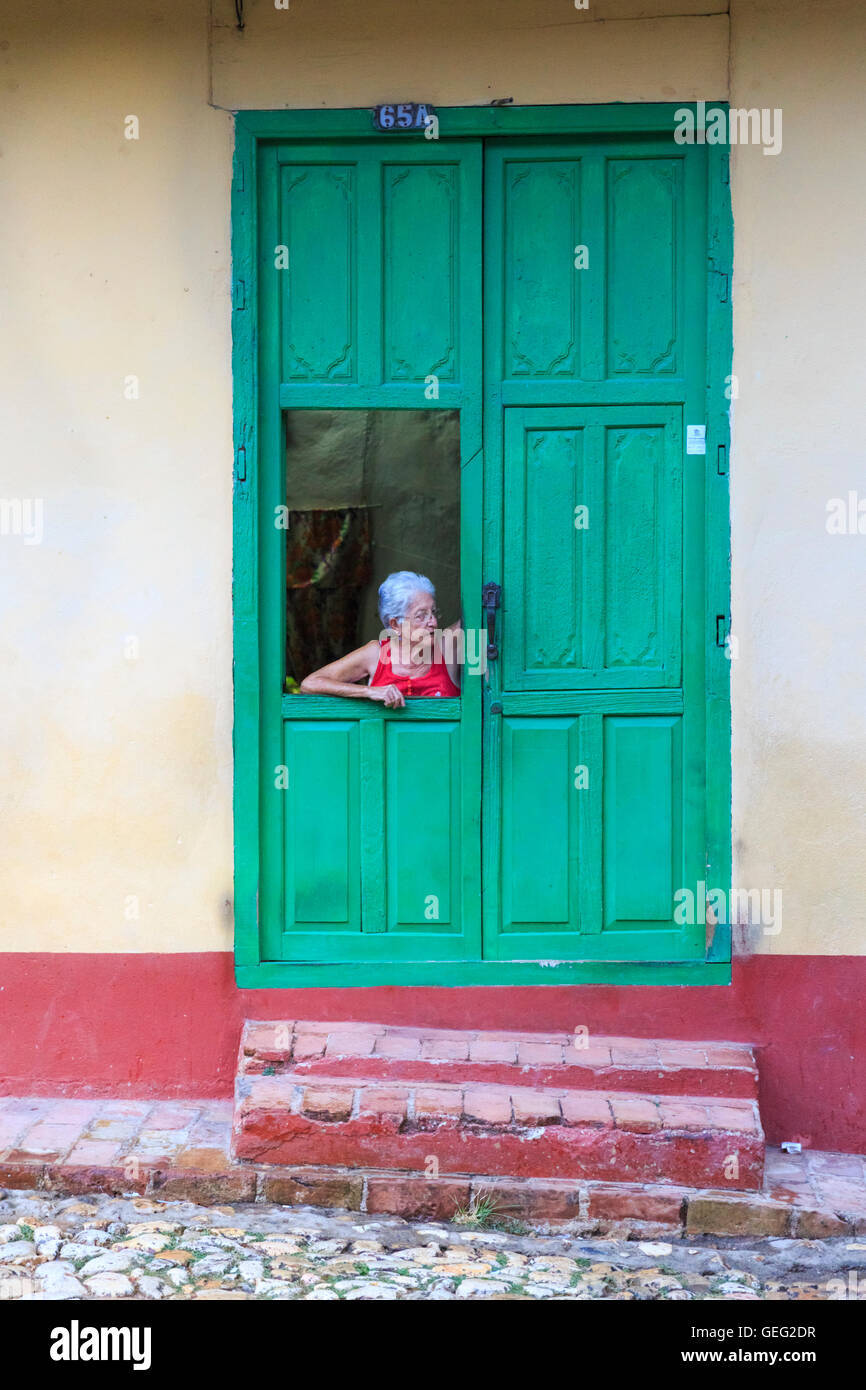 Kubanische Frau, Blick aus der grünen Fenster-Tür zu einem Haus im Kolonialstil Trinidad, Kuba Stockfoto