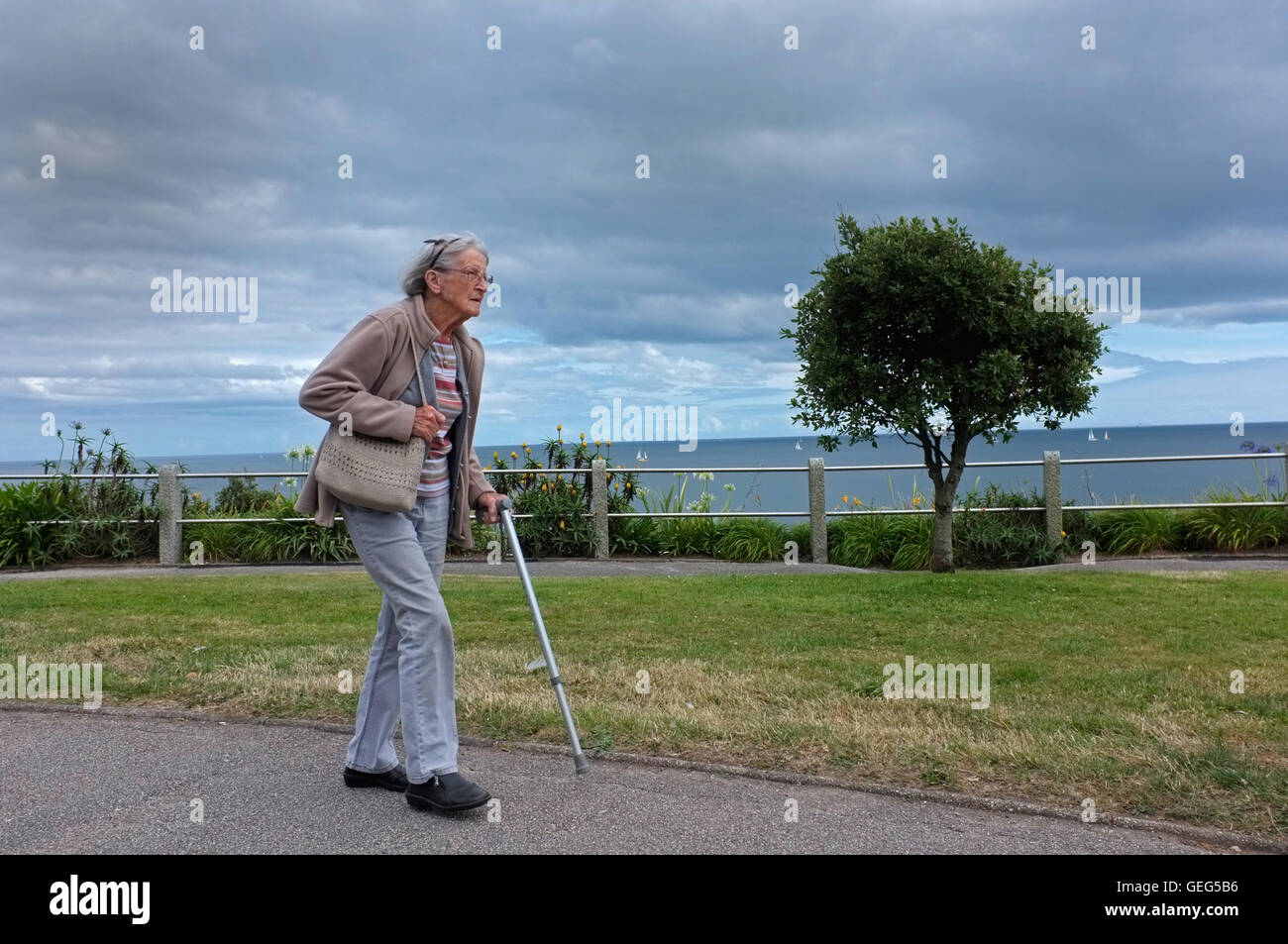 Eine alte Dame zu Fuß entlang der Strandpromenade in Falmouth, Cornwall Stockfoto
