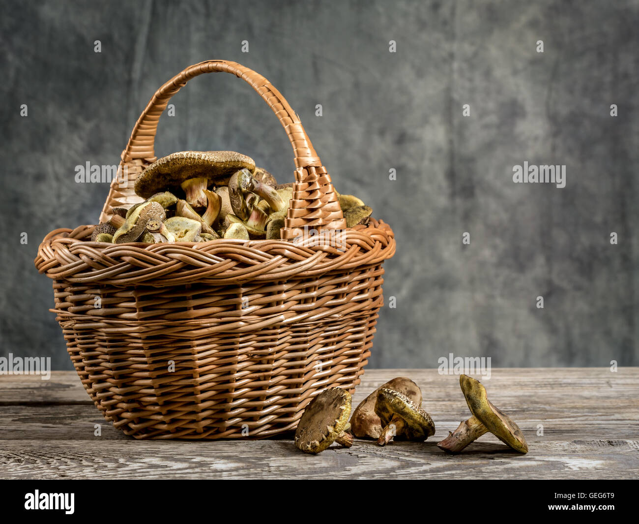 Weidenkorb voller essbarer Pilze auf Holztisch Stockfoto