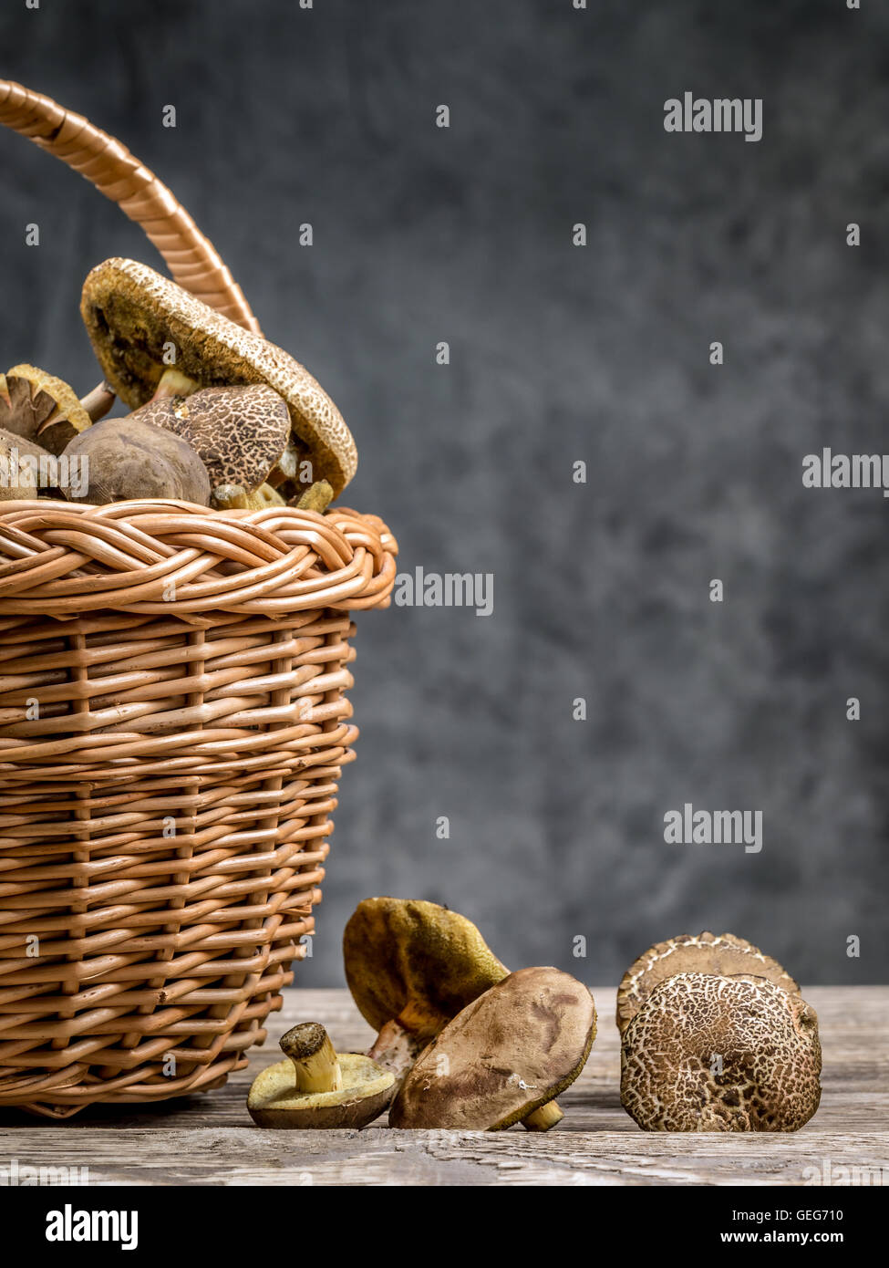 Weidenkorb voller essbarer Pilze auf Holztisch Stockfoto