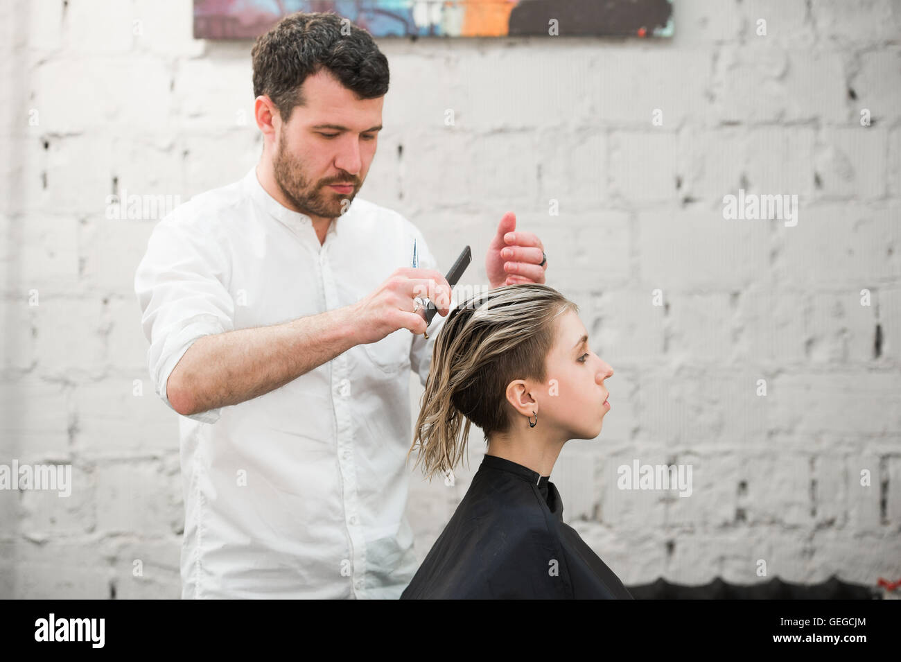 Friseur schneidet Haare mit einer Schere auf Krone schöner zufriedener Kunde in professionellen Coiffeur-salon Stockfoto