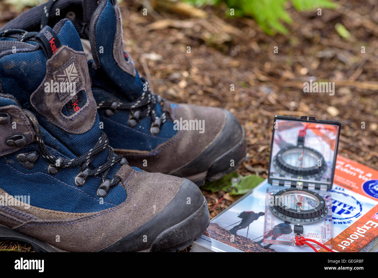 Paar Wanderstiefel mit Karte und Kompass, auf einem Waldboden. Stockfoto