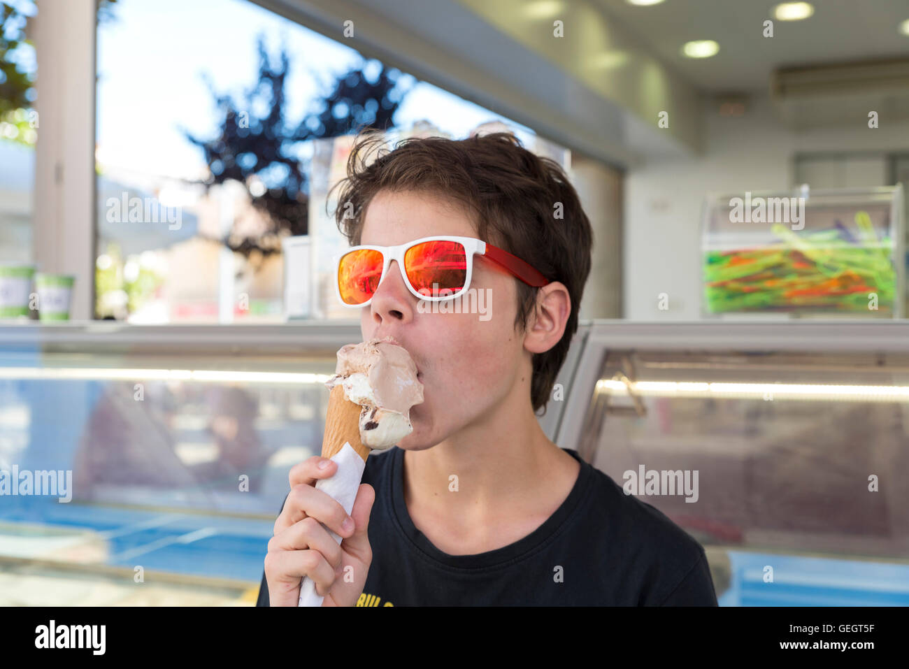 Teenager mit Sonnenbrille Eis essen Schokolade und Vanille Stockfoto