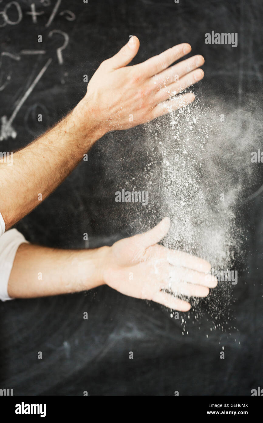 Nahaufnahme eines Bäckers stehen vor einer Tafel, seine Hände mit Mehl bestäuben. Stockfoto