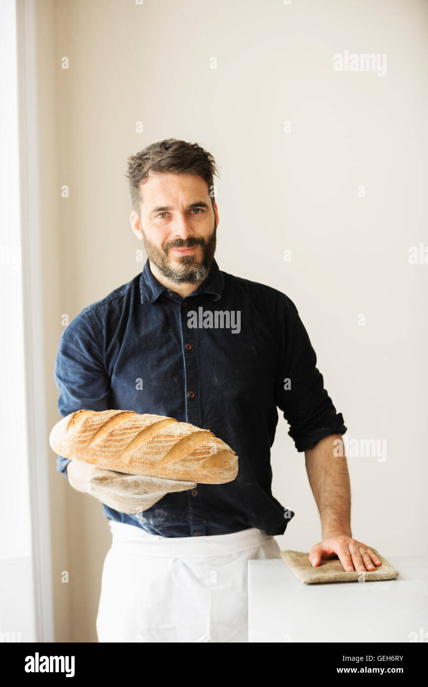 Baker, die holding zwei frisch gebackene Brote. Stockfoto