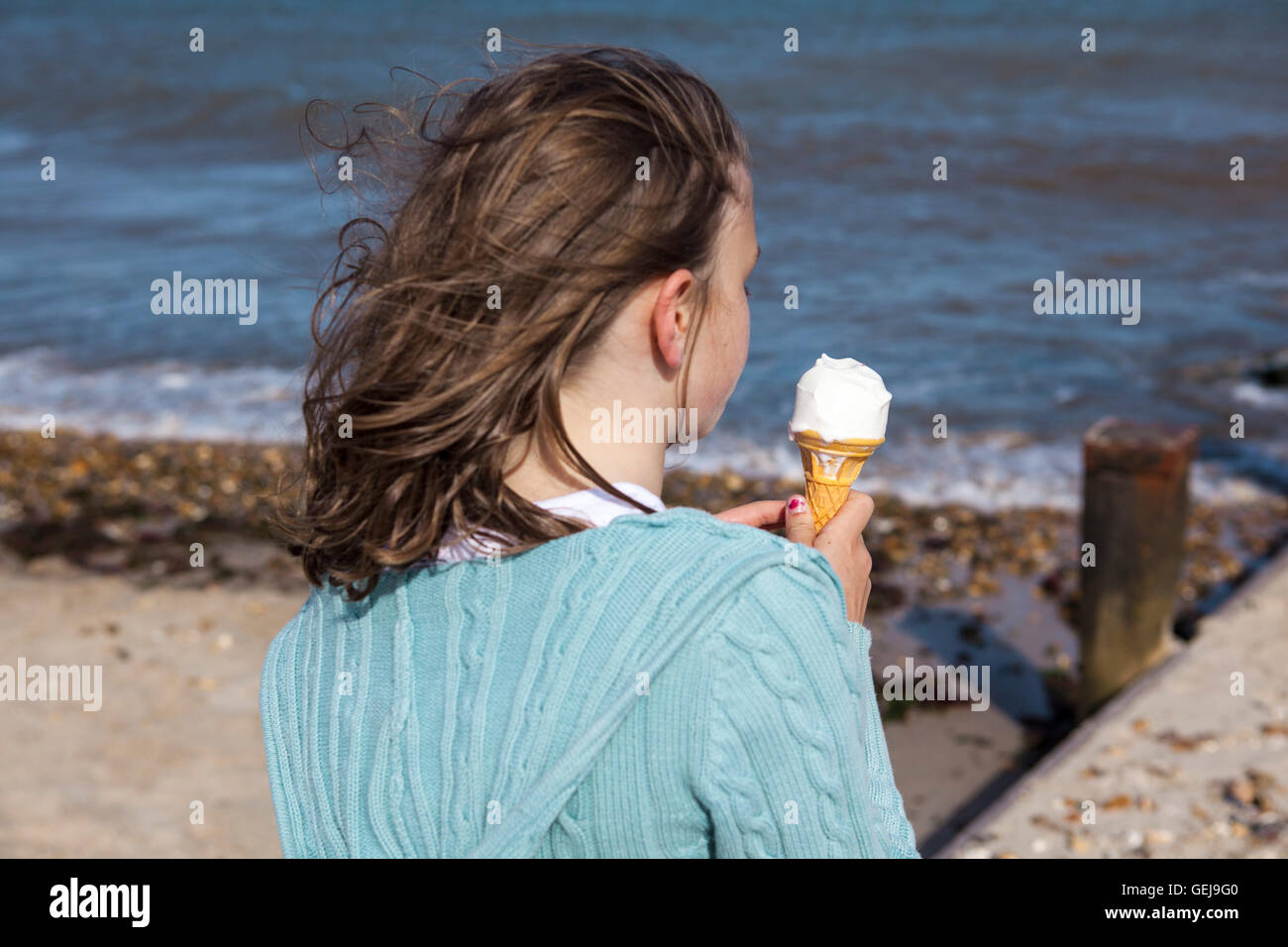 Ein junges Mädchen hält eine Eiswaffel neben der Küste. Stockfoto