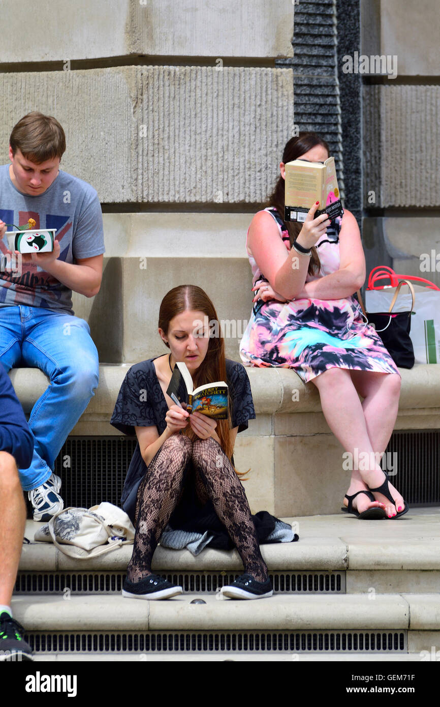 London, England, Vereinigtes Königreich. Frauen lesen von Büchern im Paternoster Square, hinter St. Pauls Cathedral während der Mittagspause Stockfoto