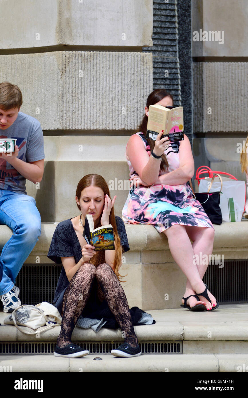 London, England, Vereinigtes Königreich. Frauen lesen von Büchern im Paternoster Square, hinter St. Pauls Cathedral, während der Mittagspause Stockfoto