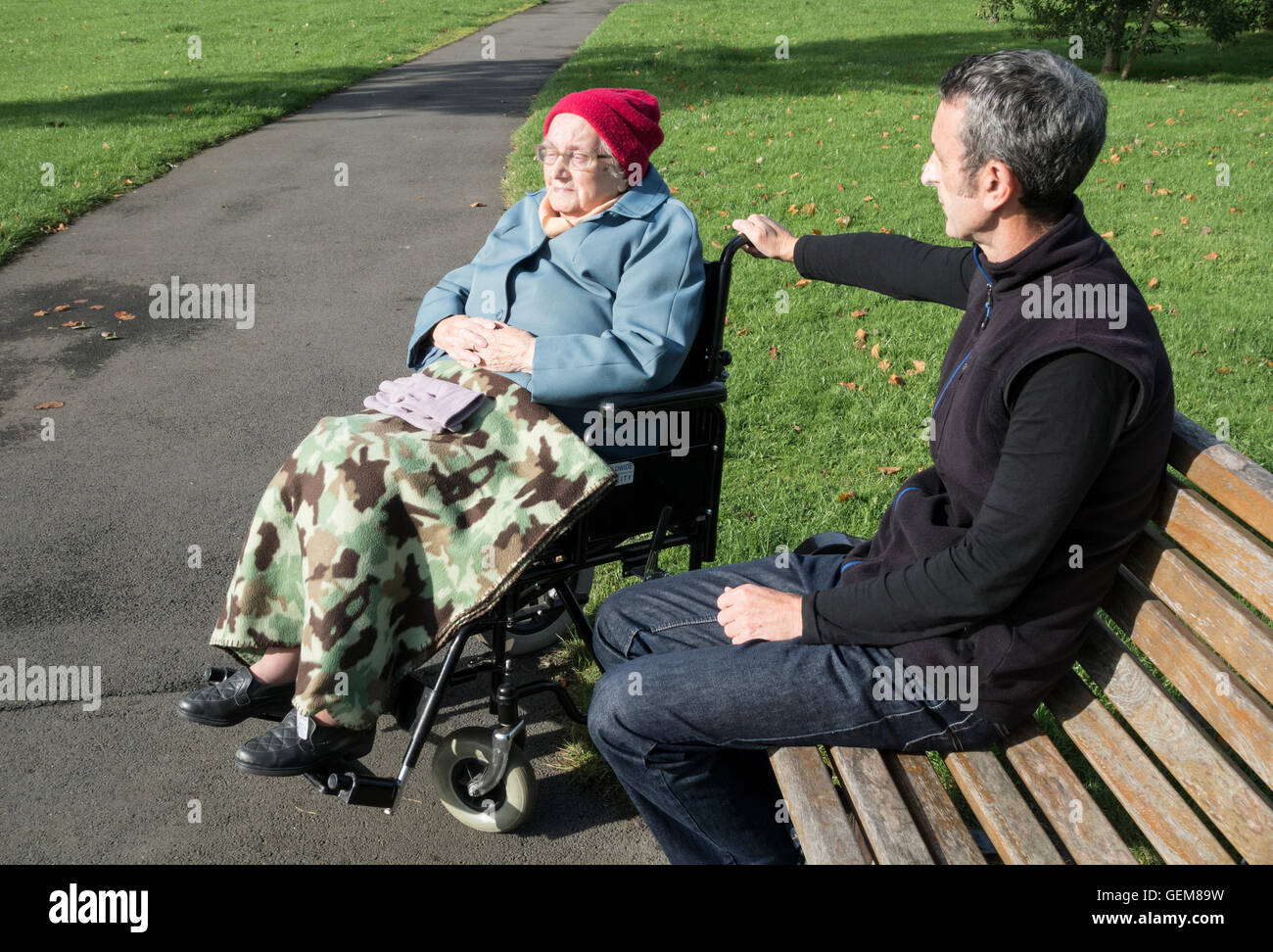 Betreuungsperson (Sohn) mit dem 90 Jahre alten Mutter im Rollstuhl in den öffentlichen Park. Großbritannien Stockfoto