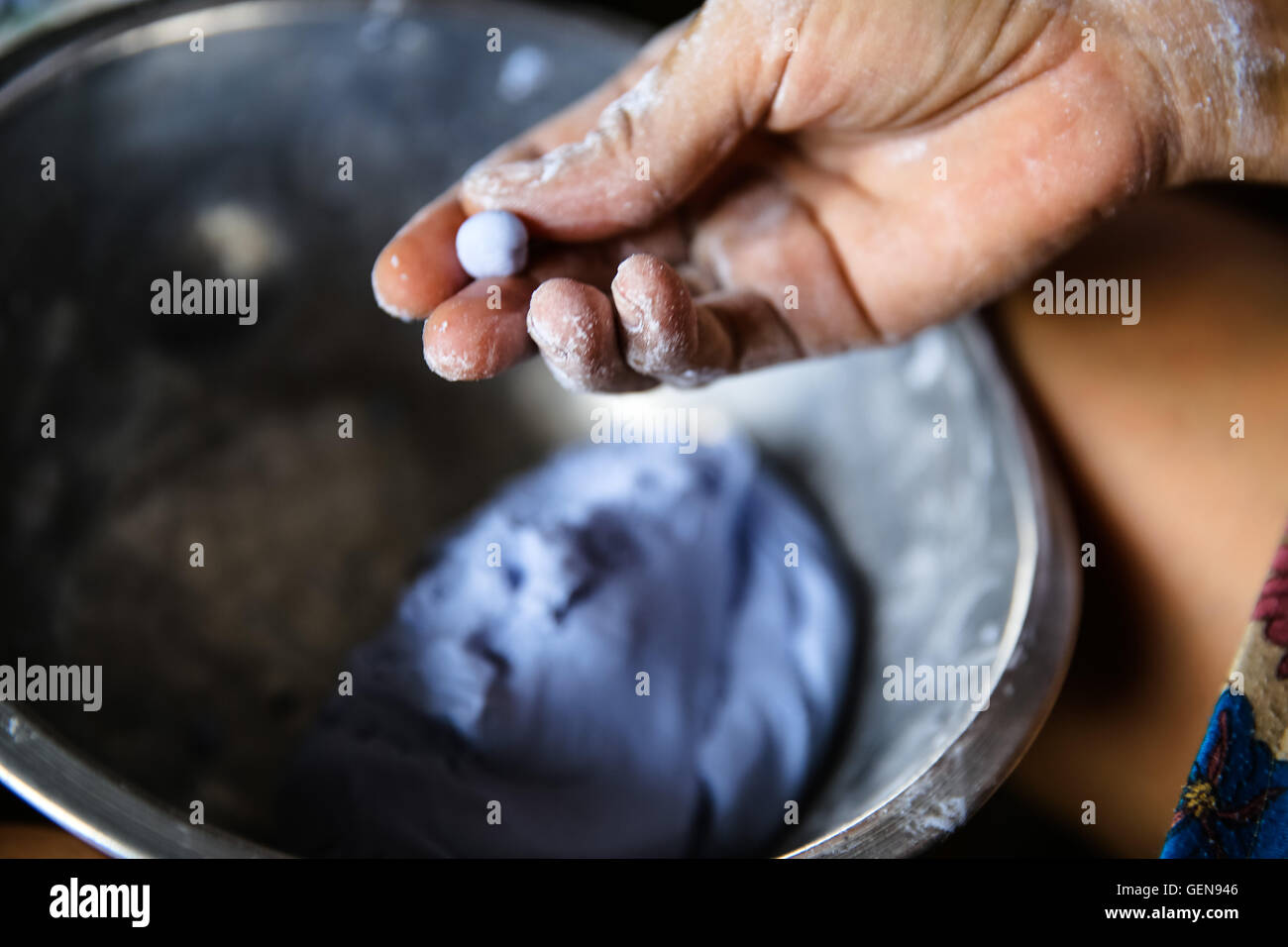 Hand mit Fingern Formen lila blau Teig Süßigkeiten Metall Schüssel mit Teig einige Oberschenkel schön Schatten nach oben gedreht Stockfoto