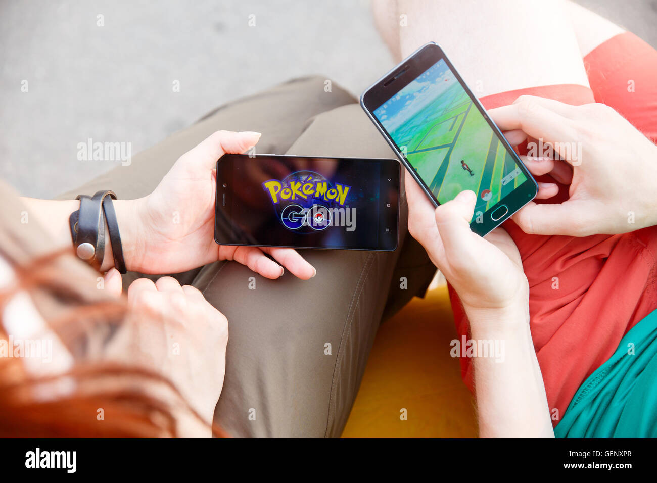 Erster Mann hielt Telefon in Händen zeigt seinen Bildschirm mit Pokemon Go app, zweite installieren dieser Anwendung. Stockfoto