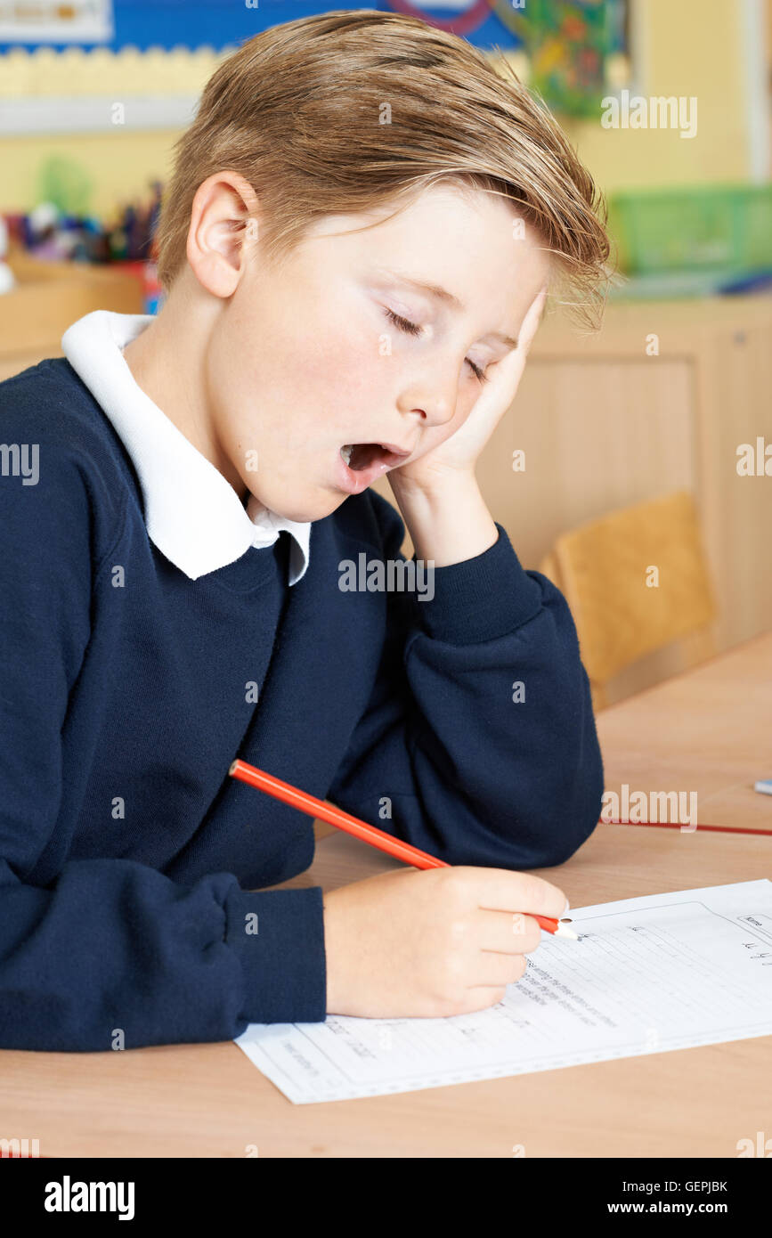 Männliche Grundschule Schüler Gähnen im Klassenzimmer Stockfoto