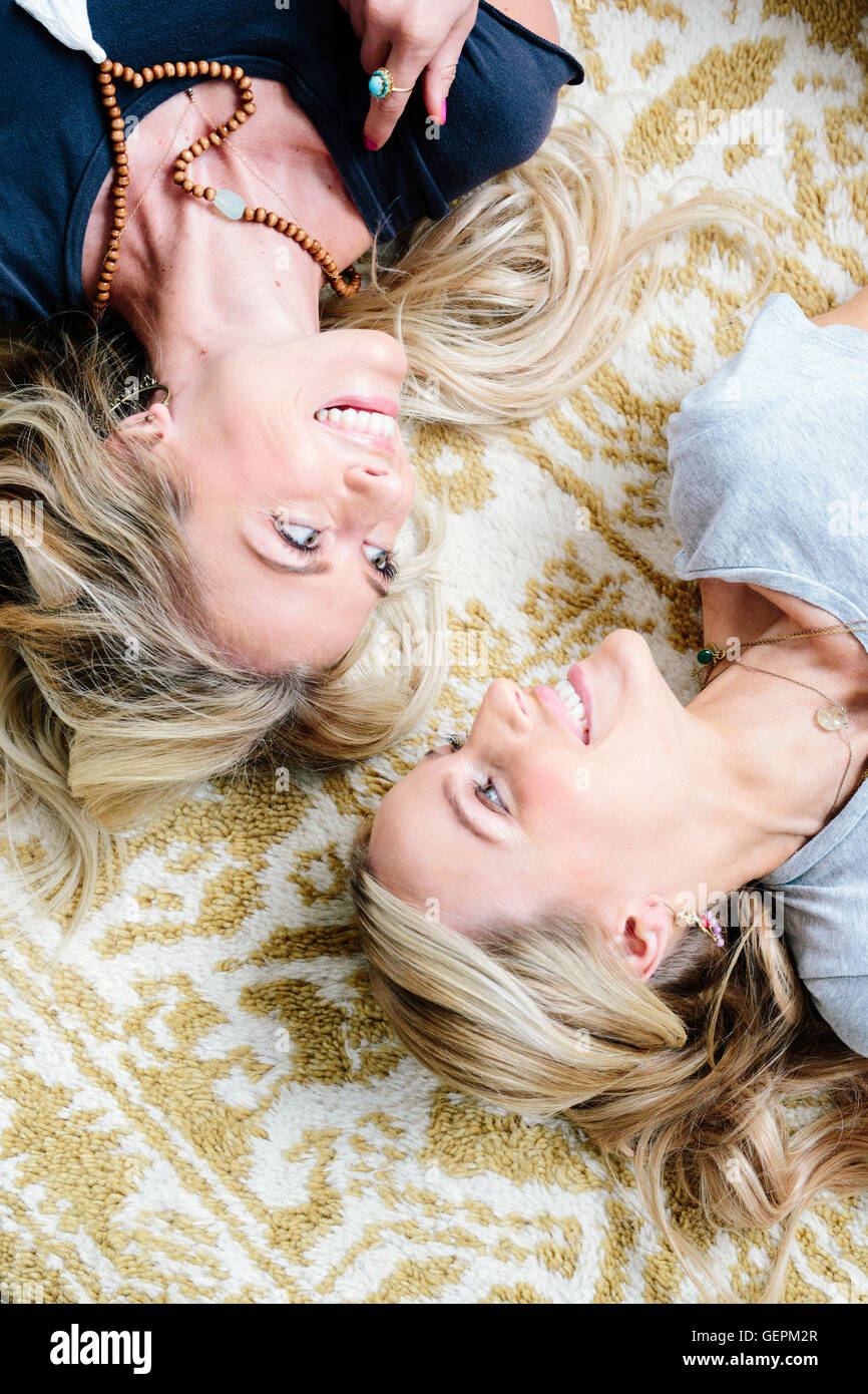 Zwei Frauen liegen auf dem Rücken einander betrachtend und lachen. Stockfoto