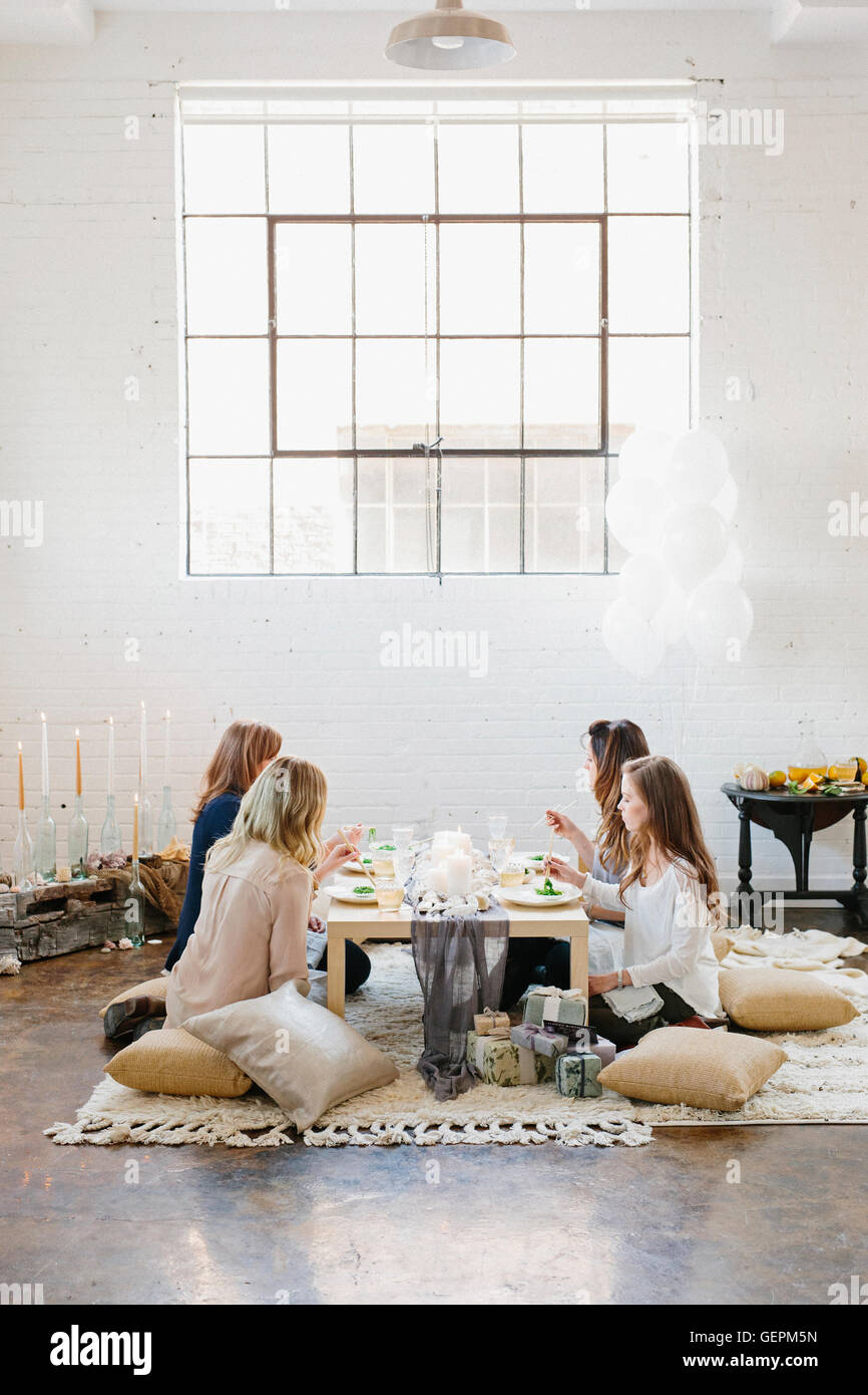 Vier Frauen an einem niedrigen Tisch auf Kissen sitzen. Stockfoto