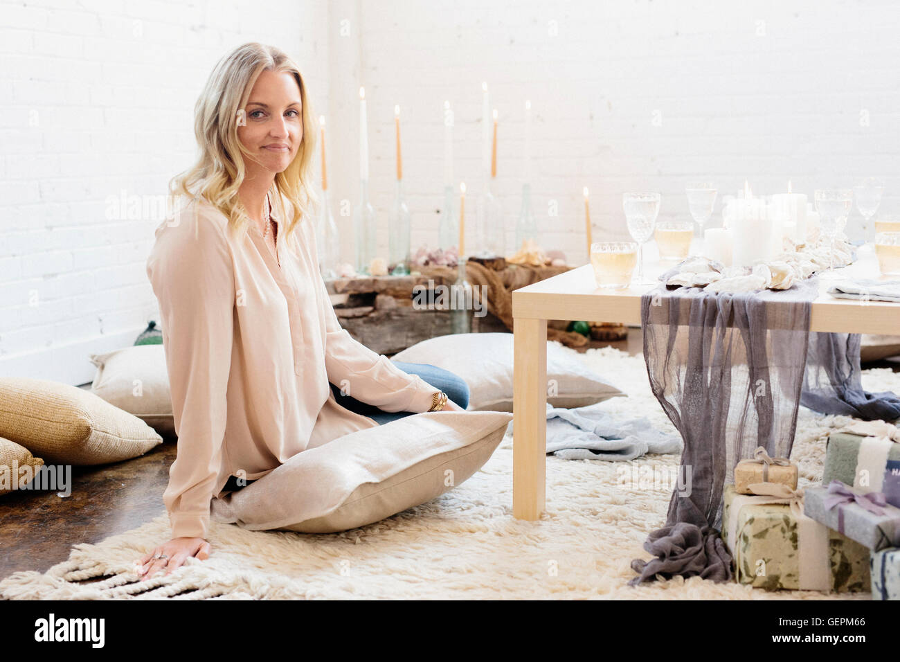 Eine Frau sitzt an einem Tisch für eine Feier Mahlzeit gelegt, beleuchtet mit Kerzen und Gläser Wein. Stockfoto