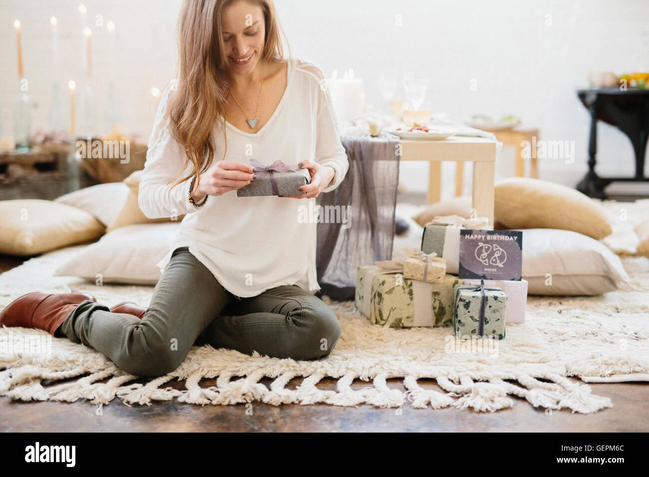 Eine Frau hält ein Geschenk verpackt Paket, auf dem Boden sitzen. Stockfoto