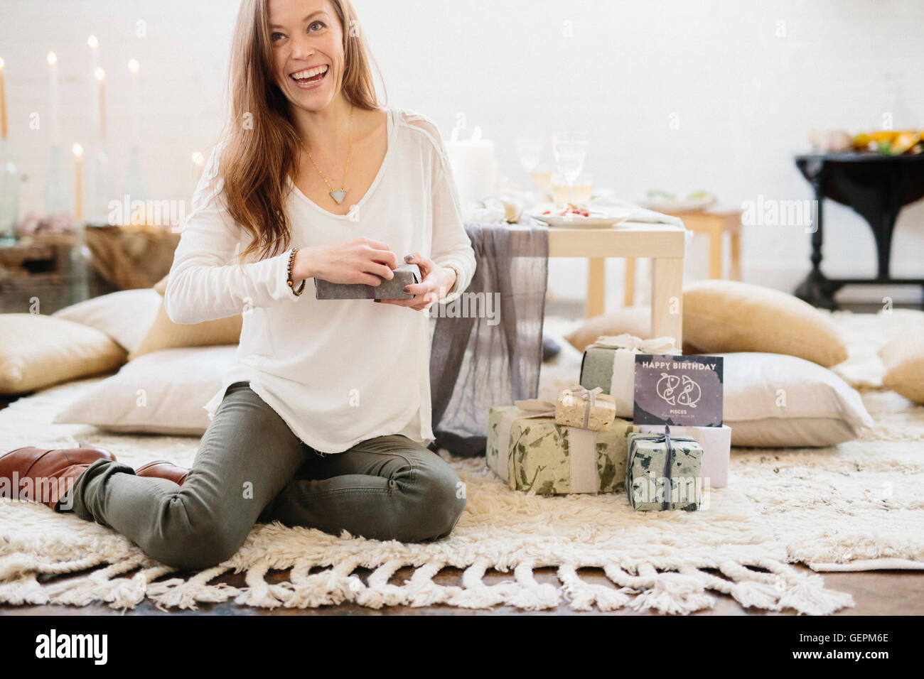 Eine Frau sitzt auf dem Boden hält ein Geschenk verpackt vorhanden. Stockfoto