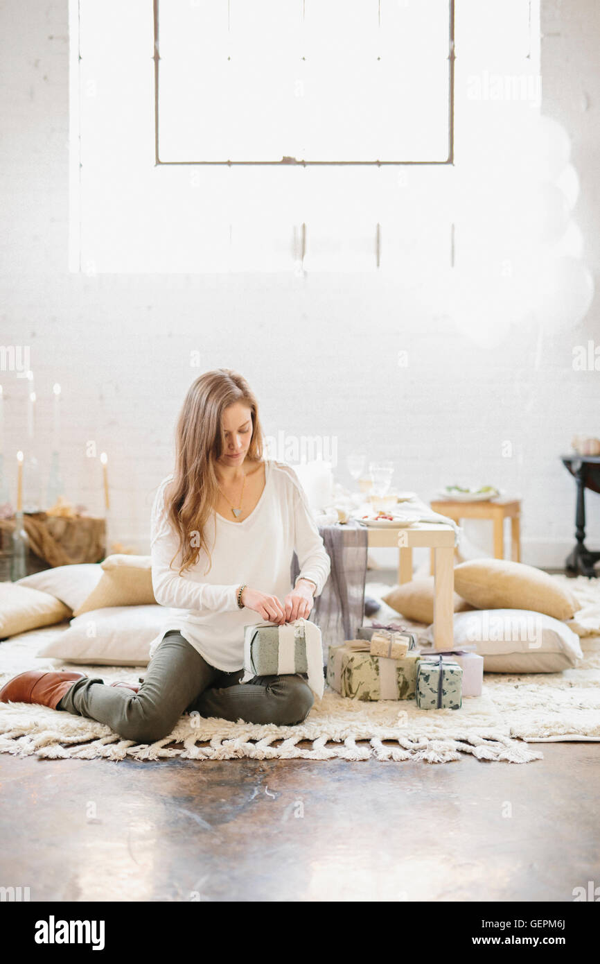 Eine Frau sitzt auf dem Boden durch einen Stapel von Parzellen, präsentiert Öffnung. Stockfoto