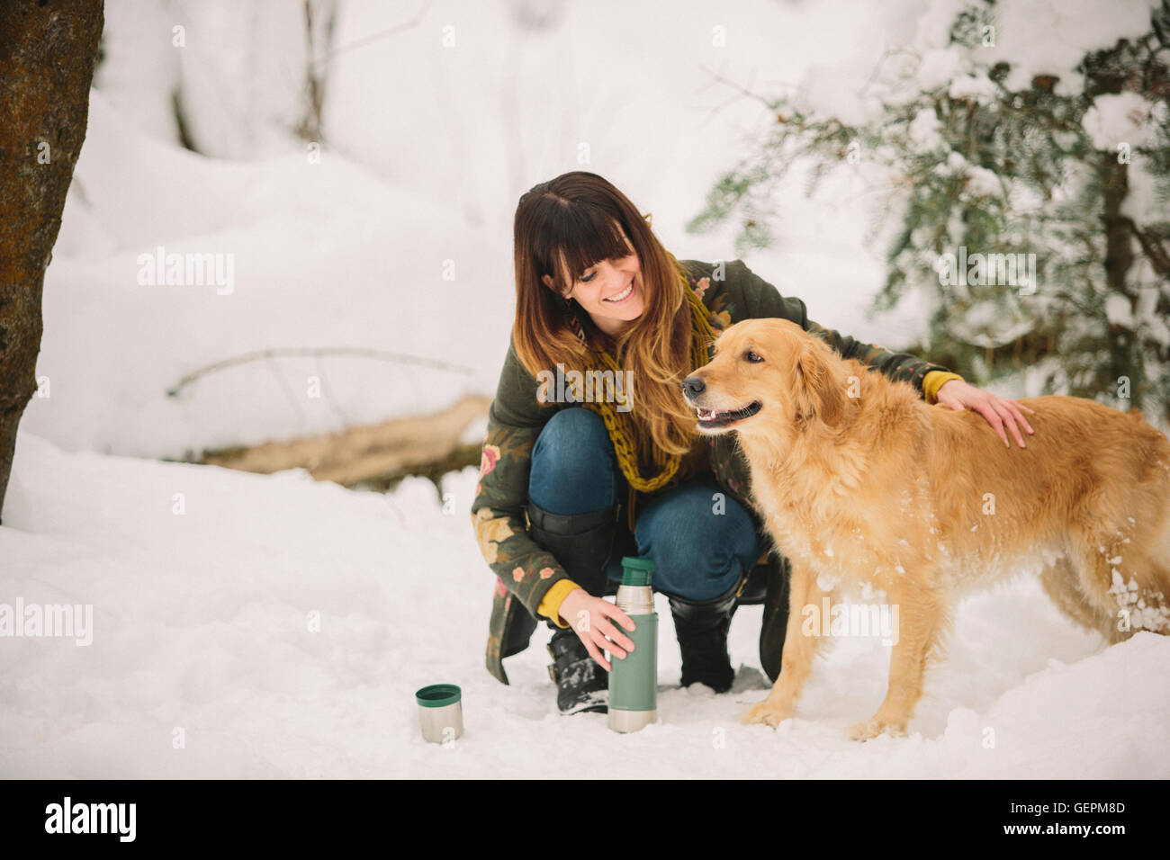 Eine Frau streicheln einen golden Retriever in Wäldern im Winter. Stockfoto