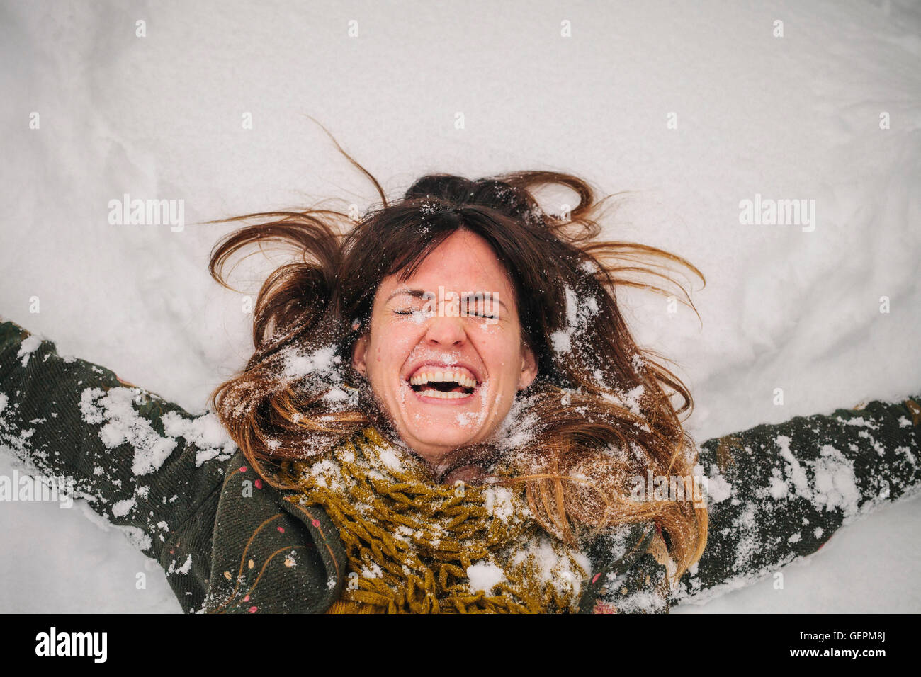 Eine Frau liegt auf einer Schneewehe Arme ausgestreckt. Stockfoto