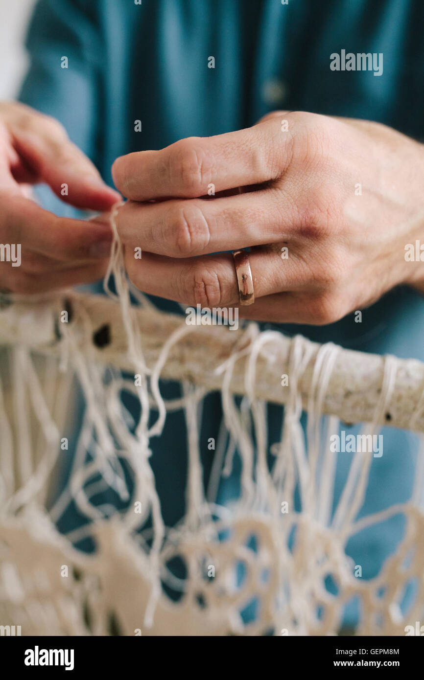 Künstler arbeiten an ein Kunstwerk auf einem Gestell hängen verknoten und Fäden weben. Stockfoto