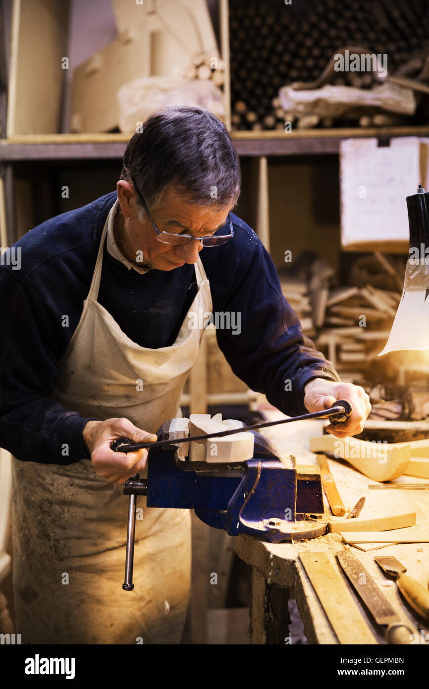 Mann, stehend auf einer Werkbank in einer Tischlerei, arbeiten an ein Stück Holz in einen Schraubstock befestigt. Stockfoto