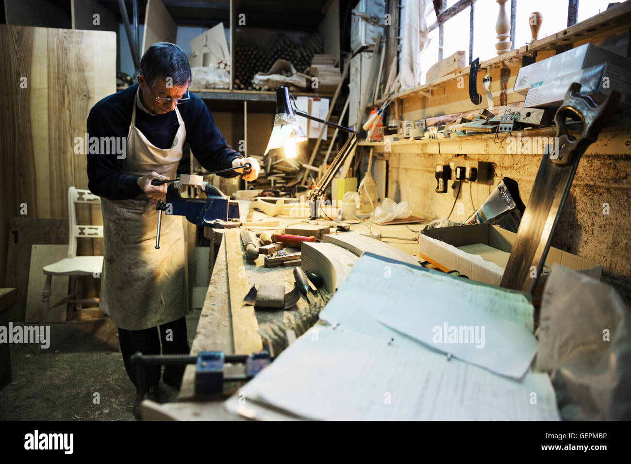 Mann, stehend auf einer Werkbank in einer Tischlerei, arbeiten an ein Stück Holz in einen Schraubstock befestigt. Stockfoto
