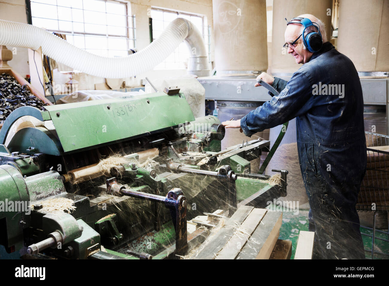 Mann in einer Tischlerei, tragen von Gehörschutz, arbeiten bei einer Holzbearbeitungsmaschine. Stockfoto