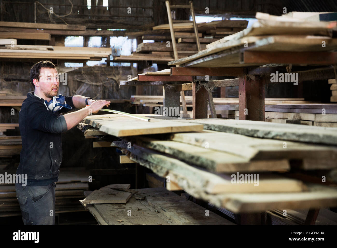 Mann arbeitet in einer Tischlerei, ein Stück Holz zu messen. Stockfoto