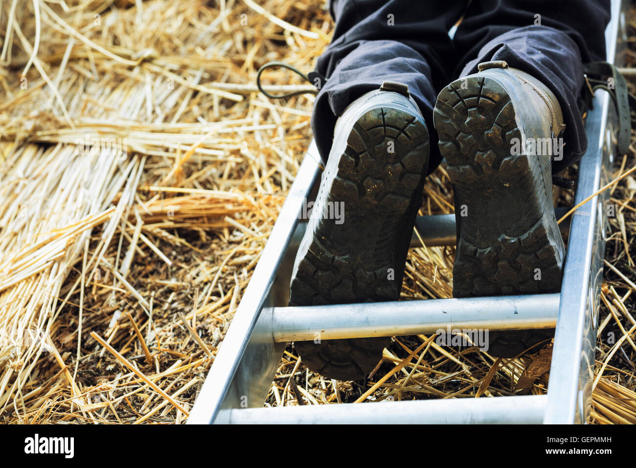 Niedrigen Winkel Blick eines Mannes thatching Dach, auf einer Leiter stehend. Stockfoto