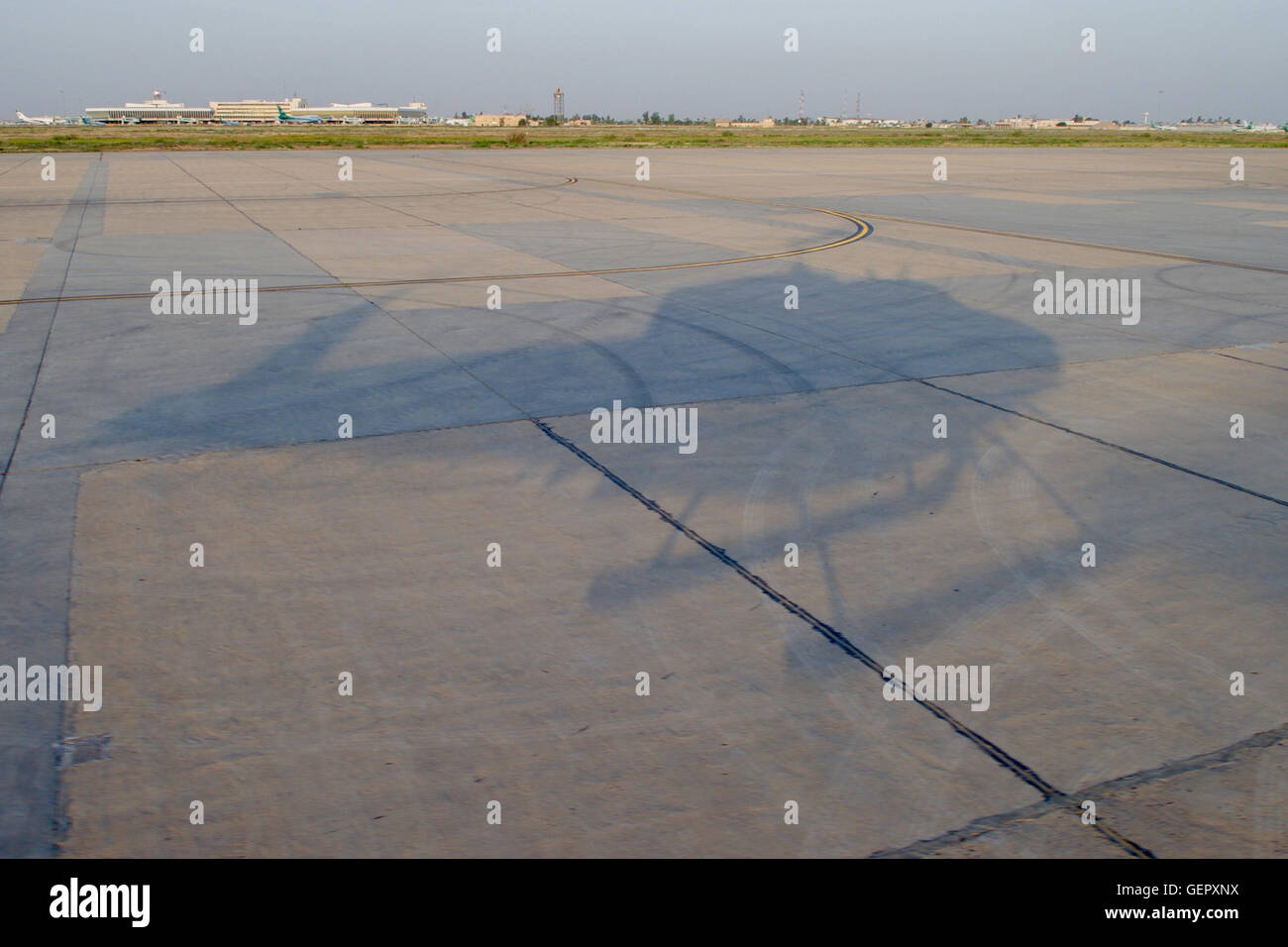 Der Schatten eines Hubschraubers mit Außenminister Kerry kreuzt den Asphalt am internationalen Flughafen von Bagdad Stockfoto