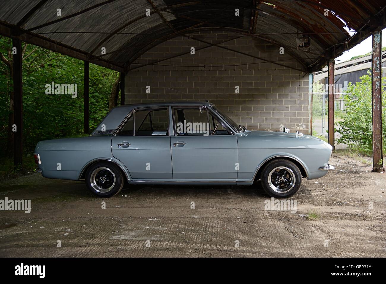 Ein 60er Jahre Ford Cortina MkII Saloon steht in einem überdachten Schuppen auf einem alten industriellen Komplex Stockfoto