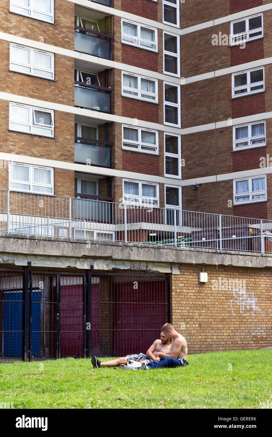 Zwei Männer sitzen auf dem Rasen vor einer Sozialsiedlung in Bedminster, Bristol Stockfoto