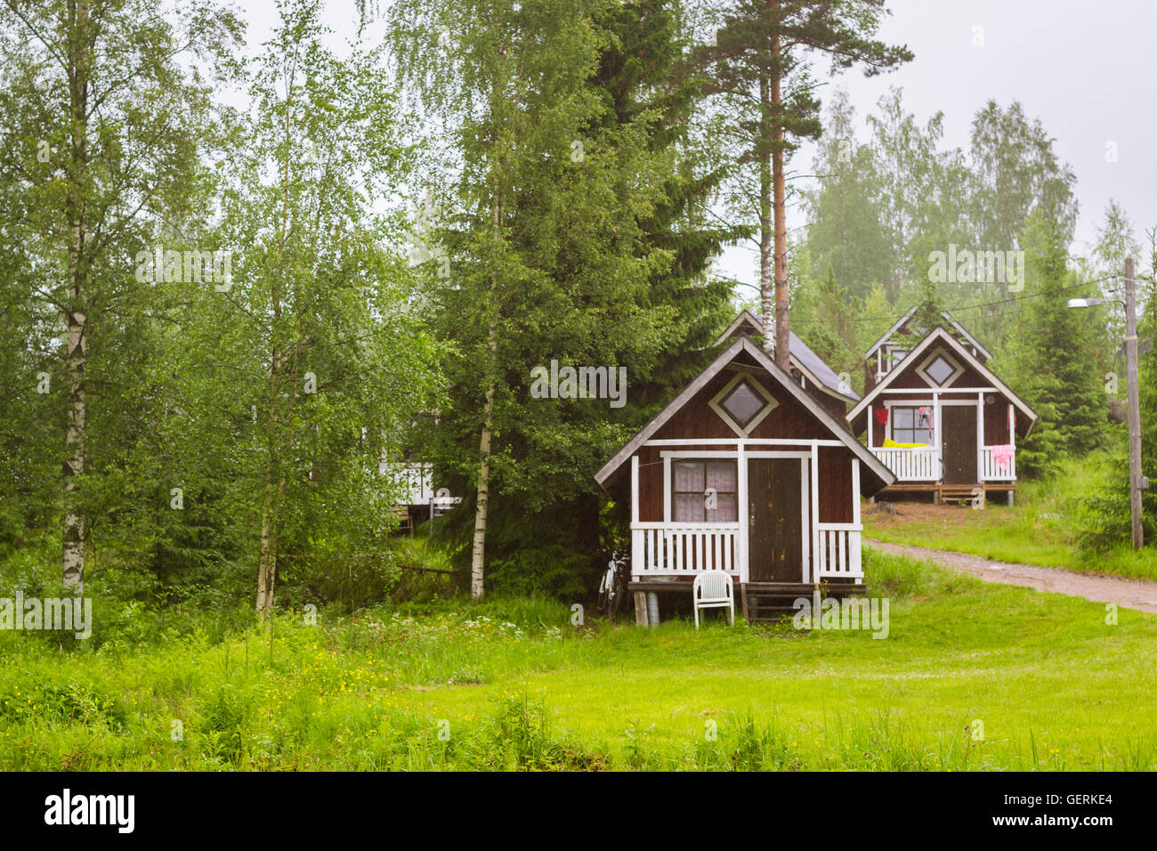 Sommer-outdoor-Aktivitäten, skandinavischen Urlaub. Kleine Holzhäuser camping unter den Sommerregen auf der grünen Wiese. Finnland Stockfoto